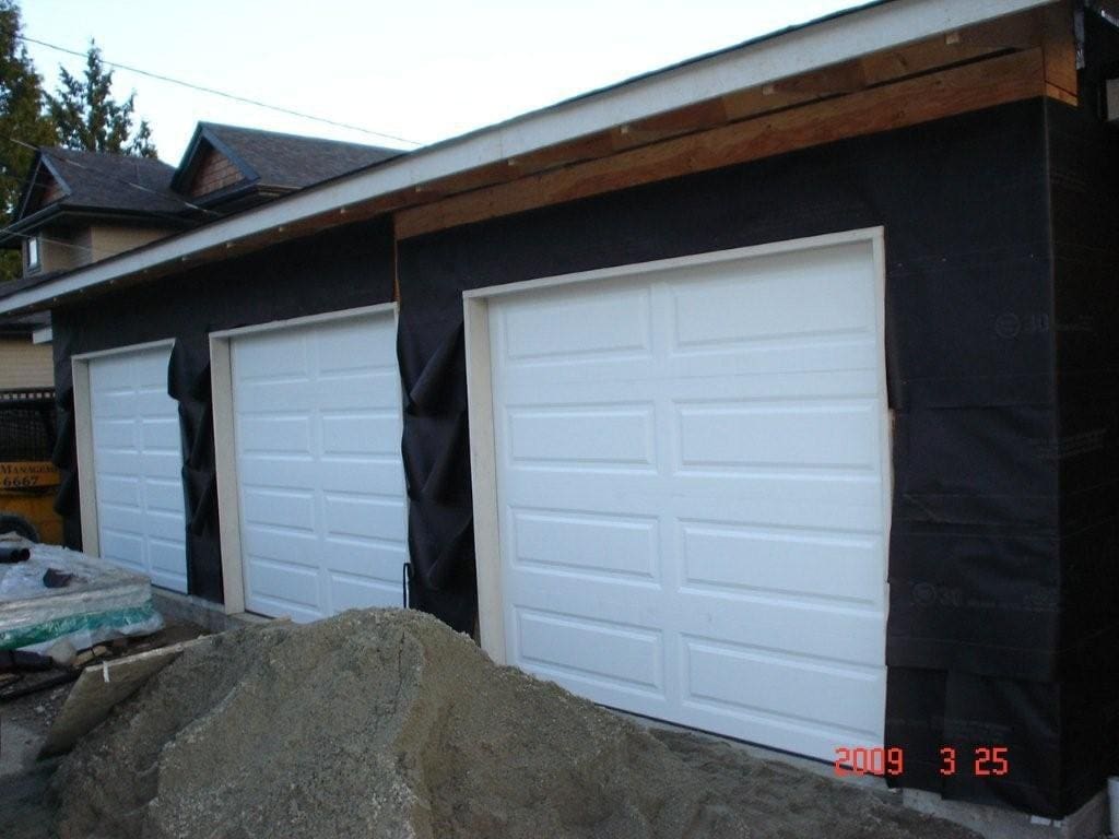 New garage construction featuring three white garage doors