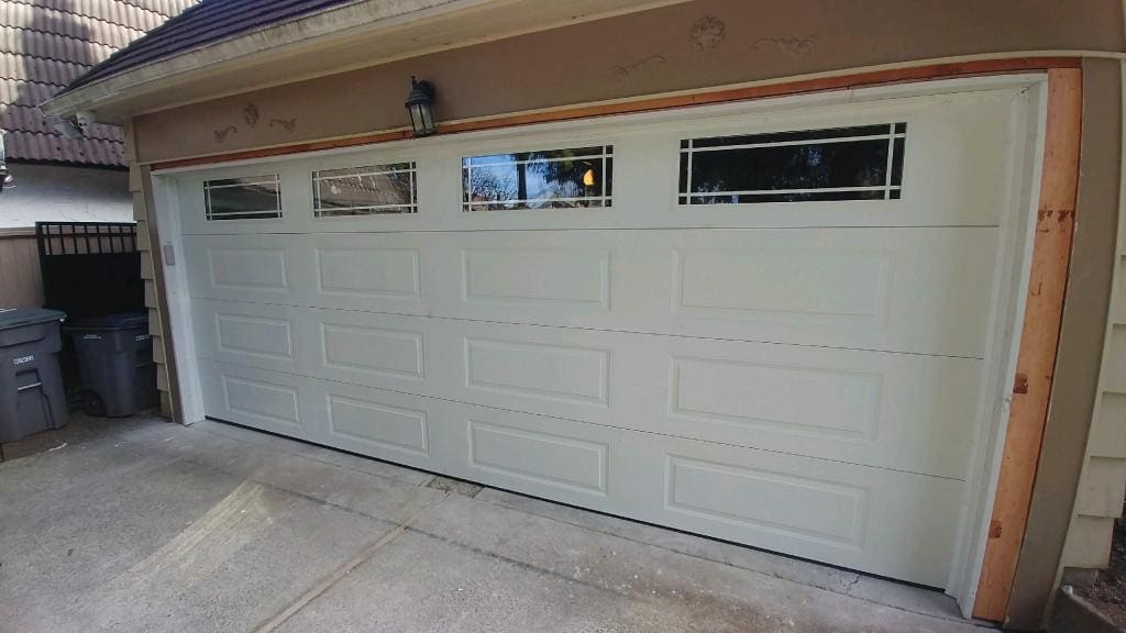 A white garage door with horizontal panels and windows at the top, set in a residential garage.